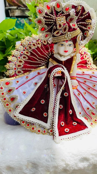 A Janmashtami special dress for Laddu Gopal Ji in white and maroon colors, with intricate Kundan embellishments,